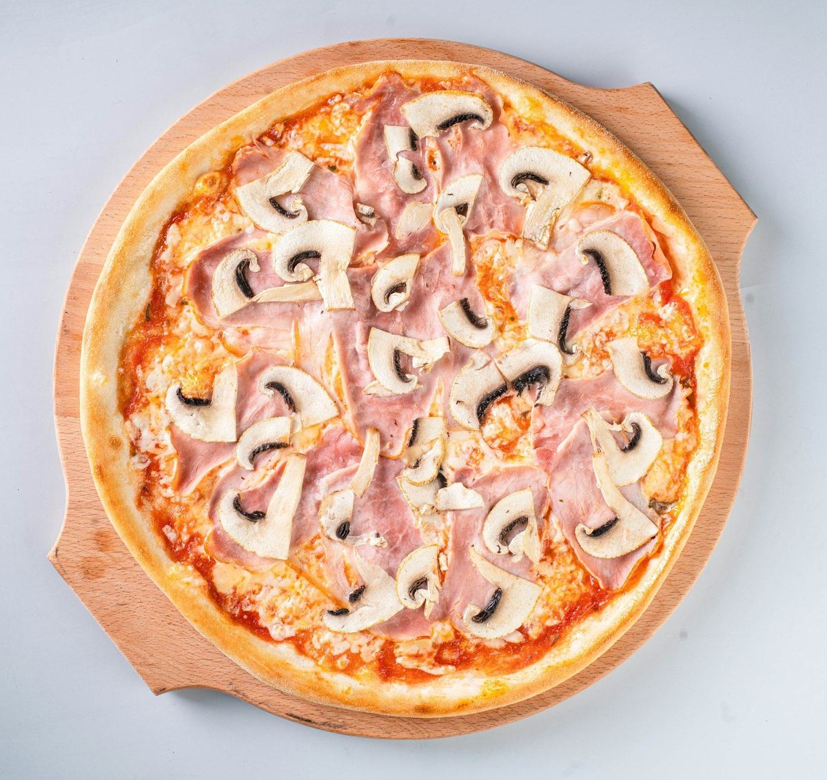Pizza jambon et champignons sur une planche en bois